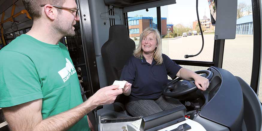 Busfahrerin überreicht Fahrgast ein Ticket