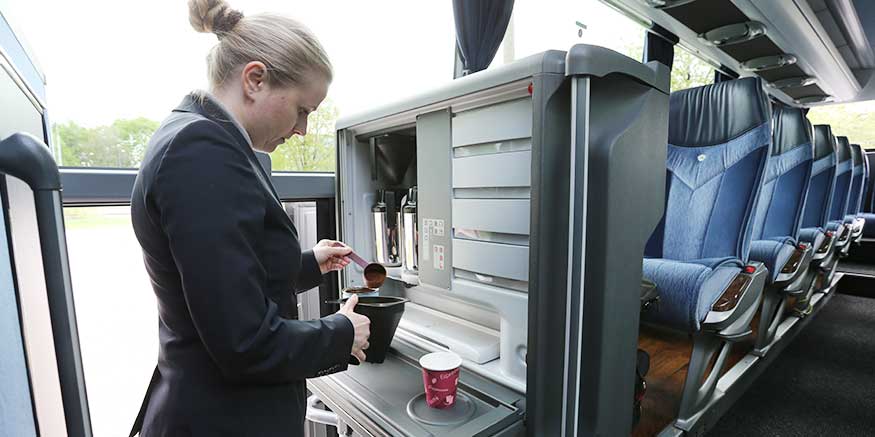 Reiseleiterin bereitet Kaffee im Reisebus zu