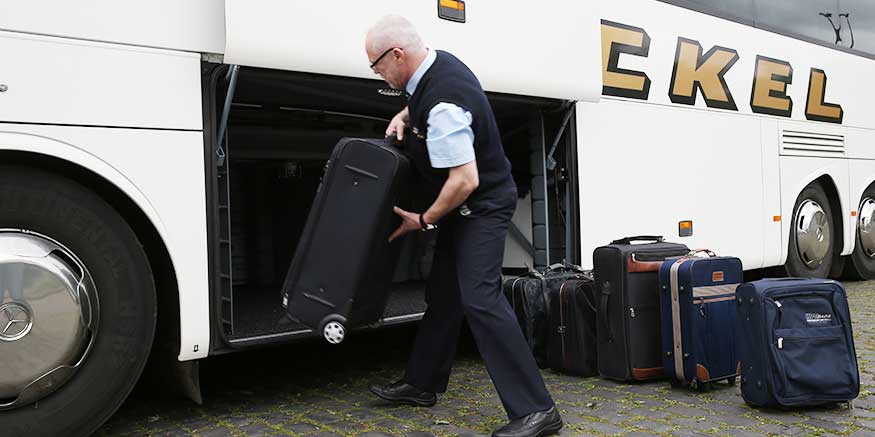 Busfahrer hebt Koffer in Ladeluke