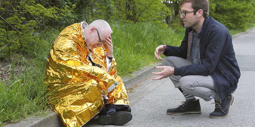 Mann redet beruhigend auf Person in Rettungsdecke ein