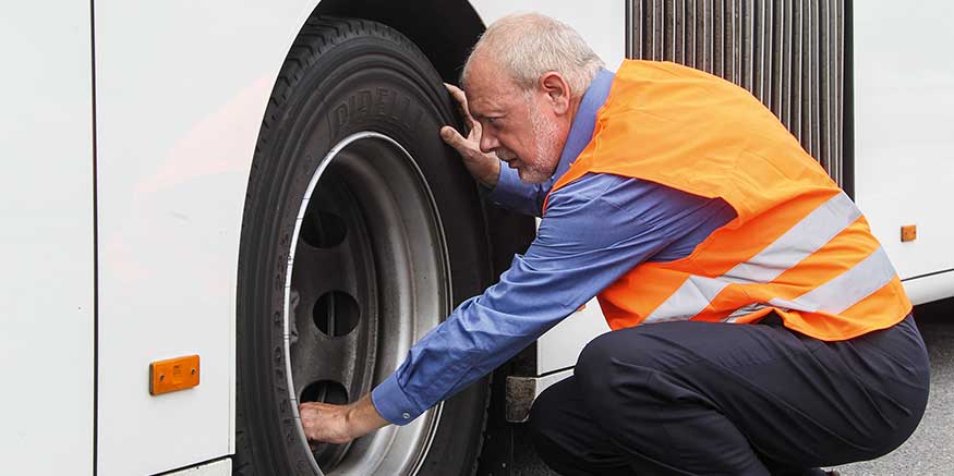 Busfahrer prüft Reifen