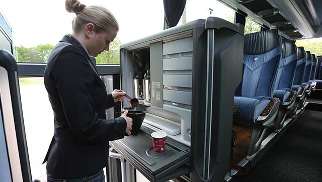 Reiseleiterin bereitet Kaffee im Reisebus zu