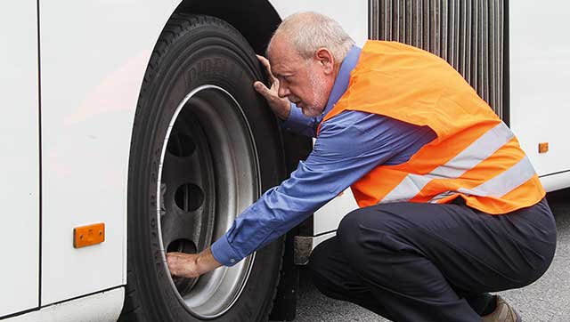 Busfahrer prüft Reifen