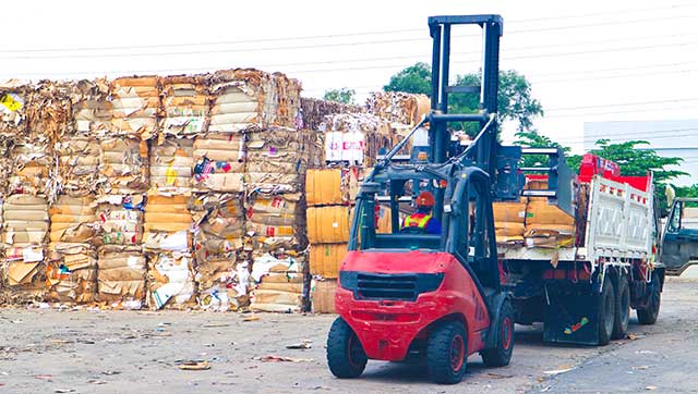 Flurförderzeug hebt Altpapier von Lkw-Ladefläche