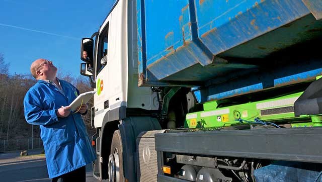 Mann mit Checkliste prüft Fahrzeug