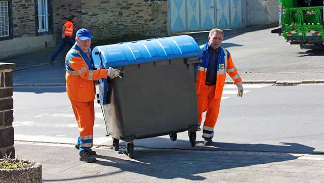 Müllwerken schieben Tonne