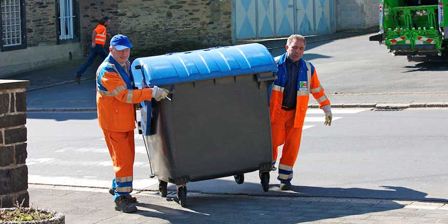 zwei Müllwerker schieben eine Tonne