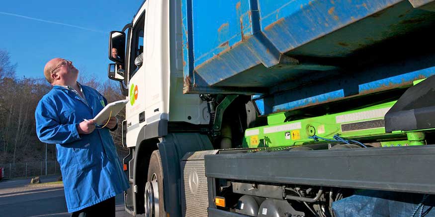 Mann mit Klemmbrett prüft Entsorgungsfahrzeug