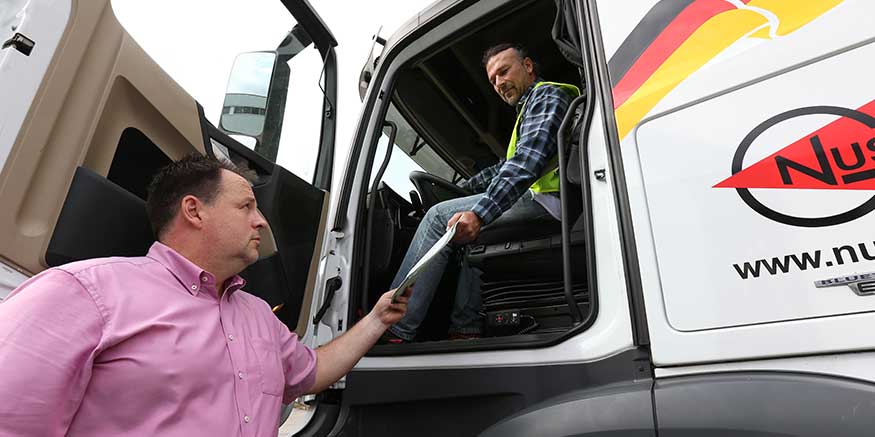 Chef überreicht Lkw-Fahrer Unterlagen