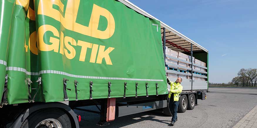 Fahrer befestigt Plane am Lkw