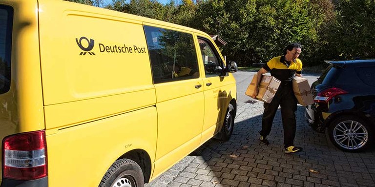 Paketzusteller neben Zustellfahrzeug