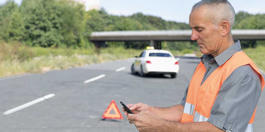 Taxifahrer mit Mobiltelefon in der Hand bei Panne