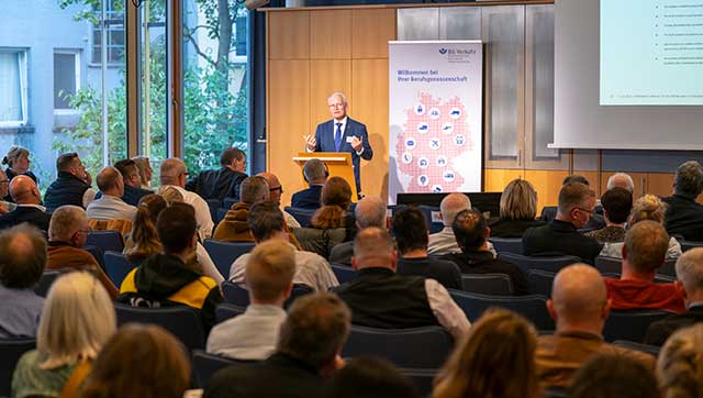 Blick von hinten auf das Publikum, das einem Redner der Branchenkonferenz zuhört.