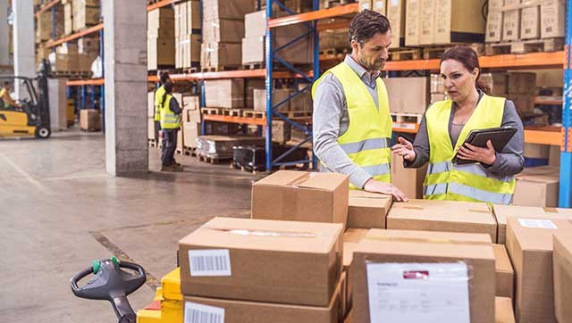 Fachkraft erklärt etwas einem Mitarbeiter im Paketdepot