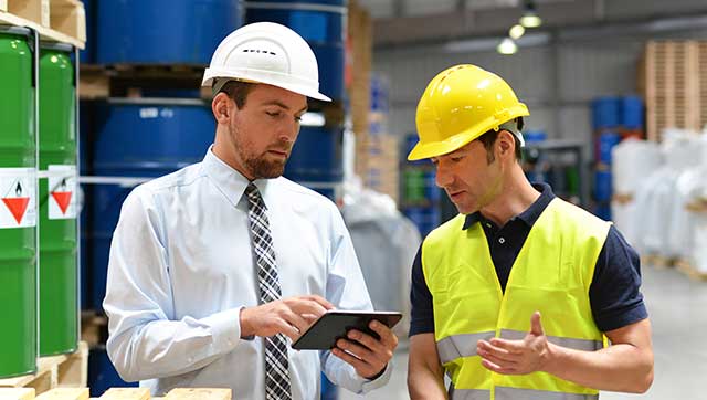 Chef und Mitarbeiter diskutieren miteinander mit Blick auf ein Tablet