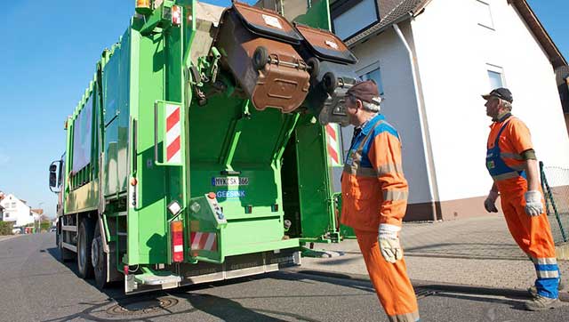 Müllwerker bei der Arbeit am Abfallsammelfahrzeug