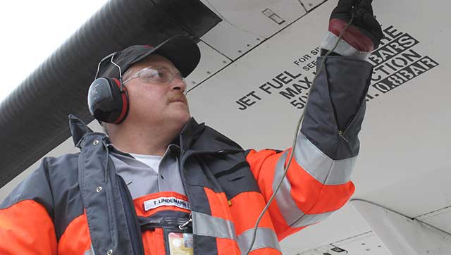 Flughafenmitarbeiter mit Gehörschutz arbeitet an Luftfahrzeug