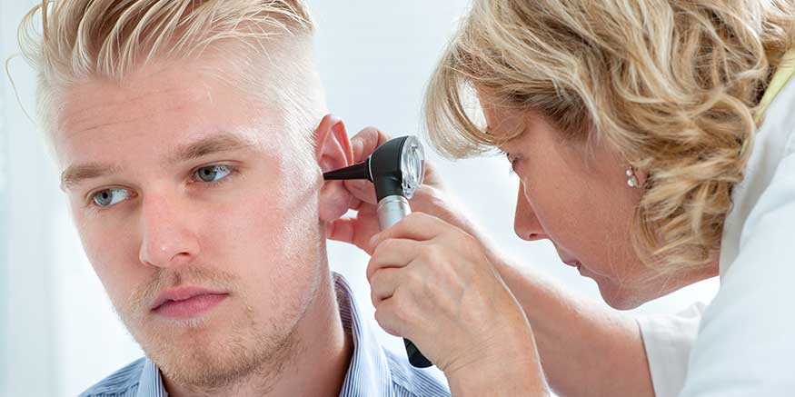 Ärztin untersucht das Ohr eines Patienten mit Otoskop
