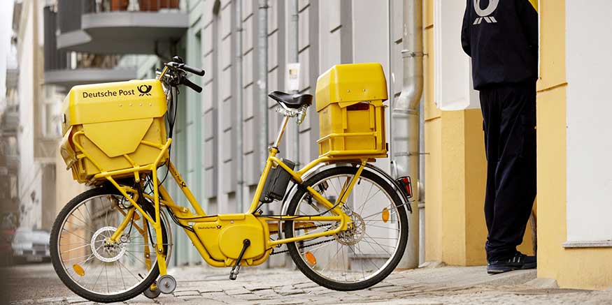 Postbote neben seinem Fahrrad