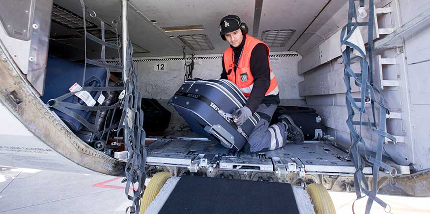 Mitarbeiter Bodencrew hebt Gepäck aus Flugzeug