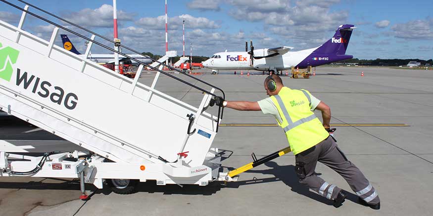 Mitarbeiter der Bodencrew zieht Gangway