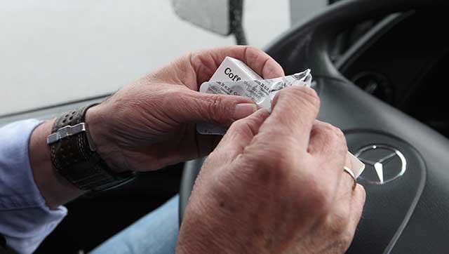 Fahrer öffnet Medikamentenschachtel hinterm Steuer