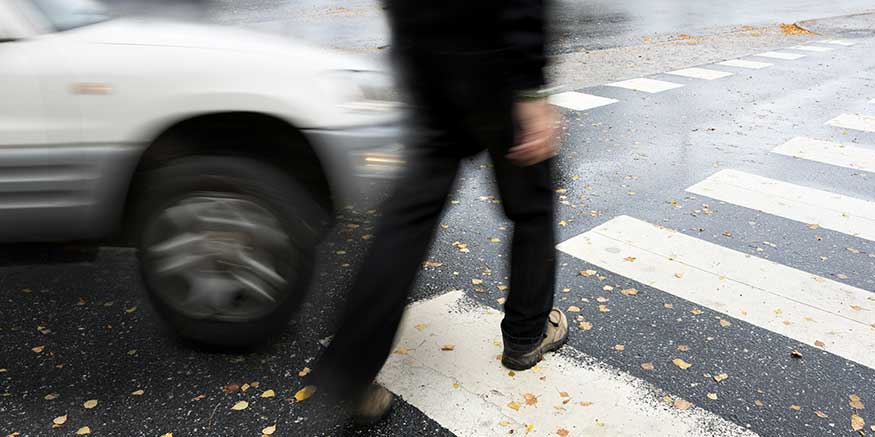 Person geht vor einem Auto über den Zebrastreifen